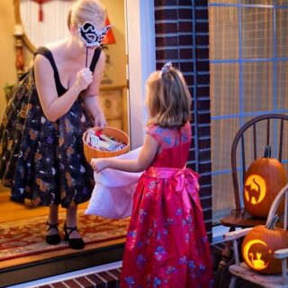 woman greets princess girl for trick or treat