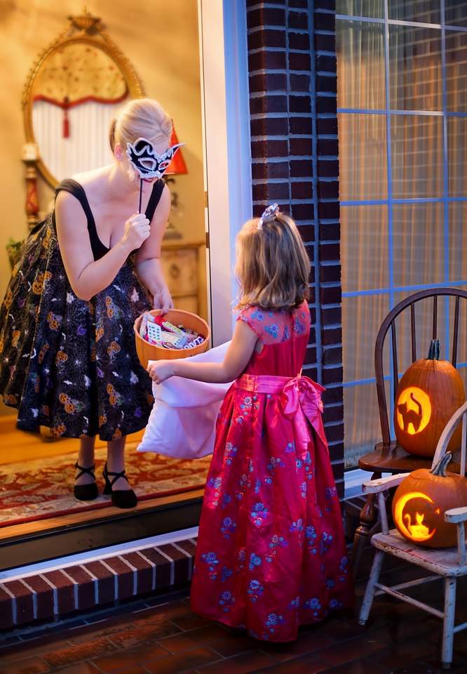 woman greets princess girl for trick or treat