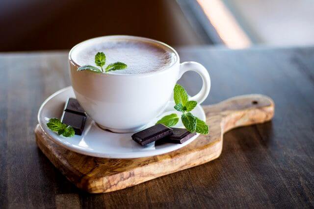mint sprigs around a cup  of hot coffee