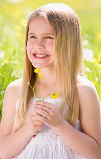 girl holding buttercups to her chin